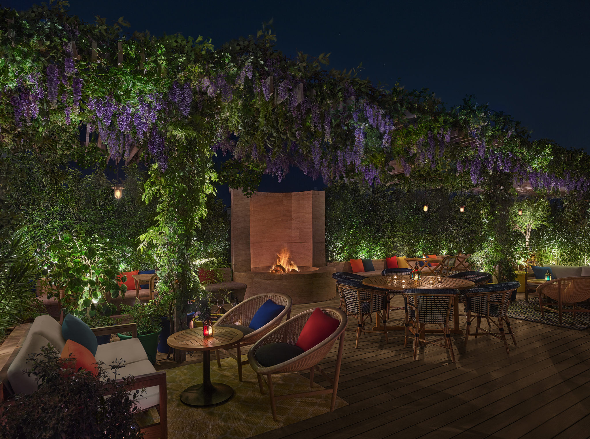 Outdoor dining area with hanging garden and fireplace at night