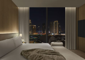 Guest room with city view and fur throw on bed at night