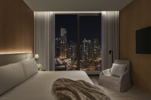 Guest room with city view and fur throw on bed at night