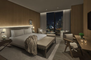 Guest room with city view and fur throw on bed at night