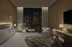 Guest room with city view and fur throw on bed at night